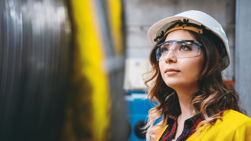 Woman in the storage room with helmet and goggles Woman in the storage room with helmet and goggles, looking upwards to the left